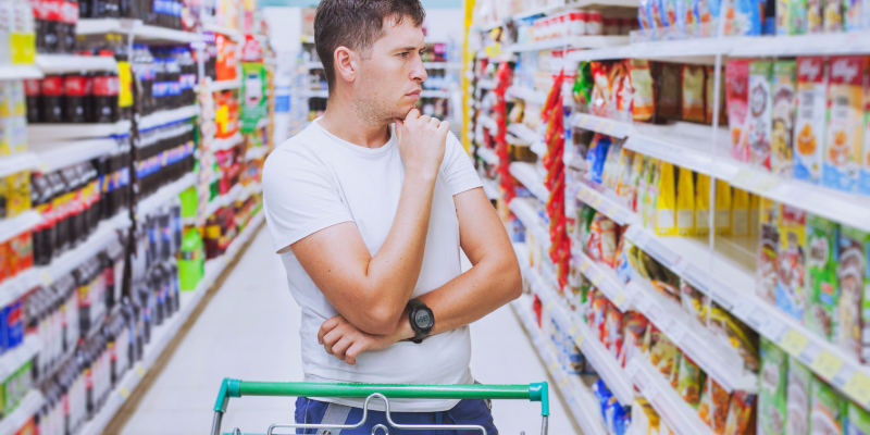 confused man with shopping cart in supermarket