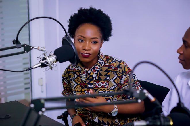 Woman with natural hair and patterned shirt hosting a podcast.